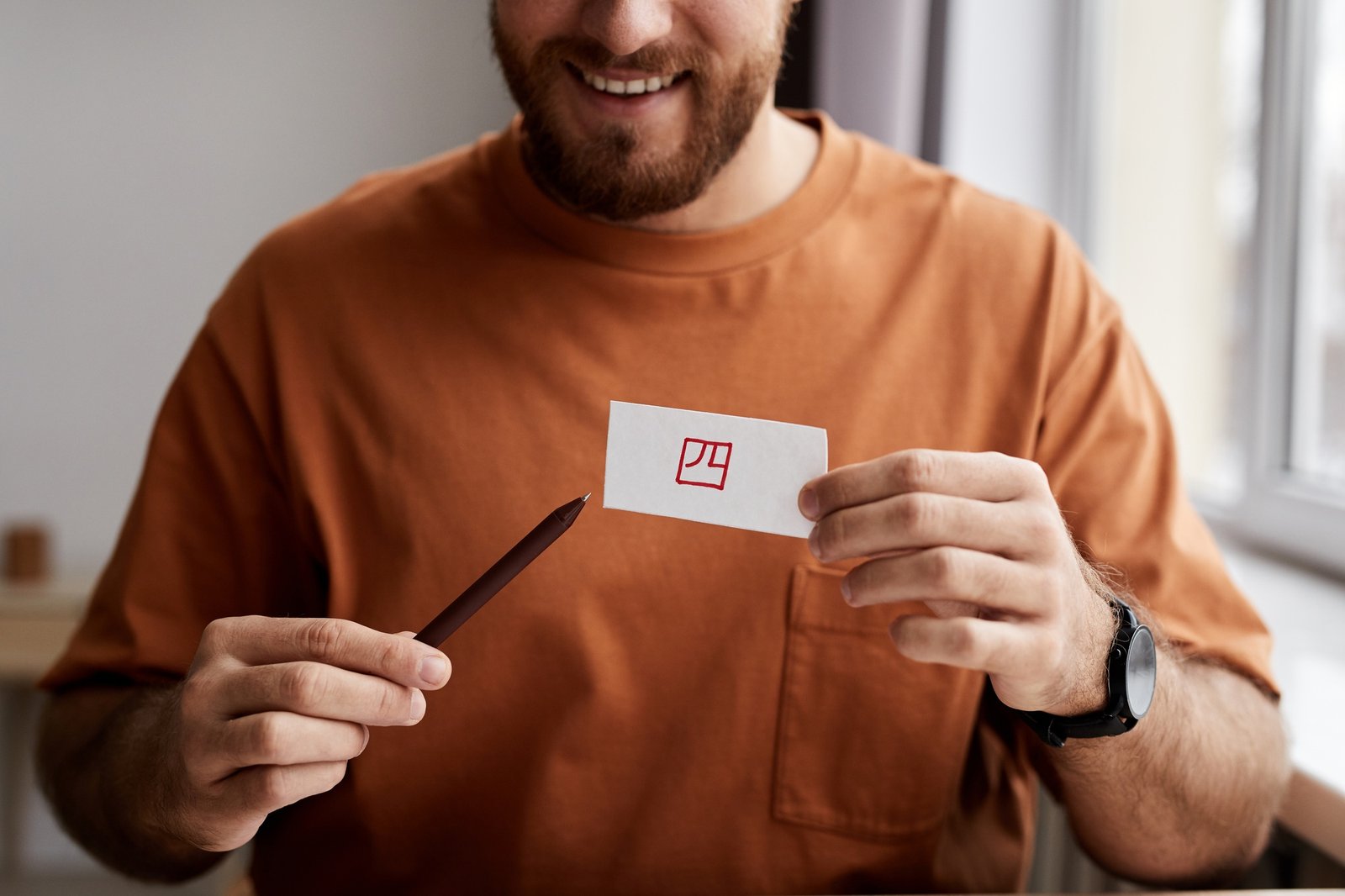 Close-up of smiling young man showing paper card with hieroglyph